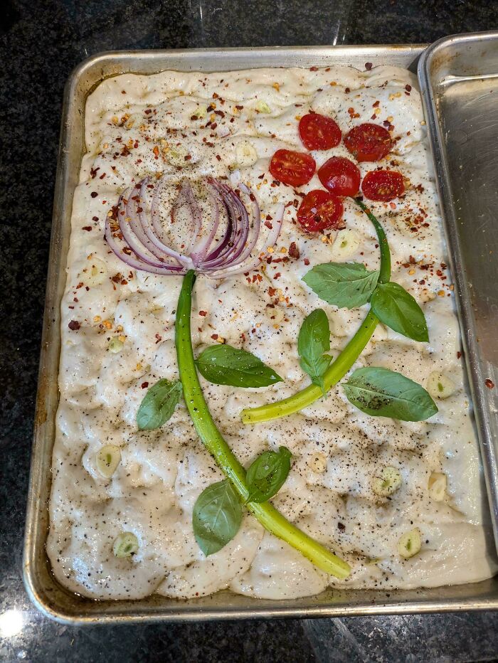 Creative baking art on focaccia dough with tomato and onion flower design, showcasing culinary concoctions elevated.