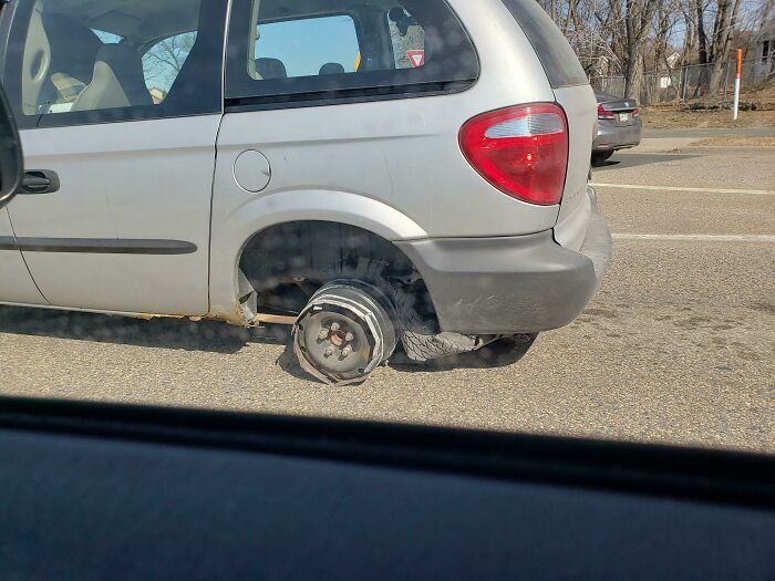 Minivan driving with a missing rear wheel, showcasing poor car maintenance.