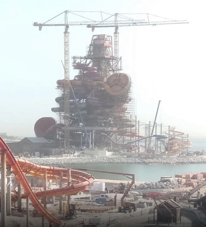 Gigantic waterpark under construction with towering slides and cranes, showcasing scarily big structures for megalophobia fans.
