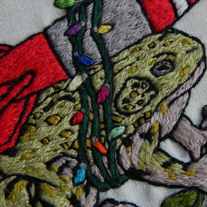 Close-up of a detailed embroidery design featuring a colorful spotted frog with vibrant stitched accents.