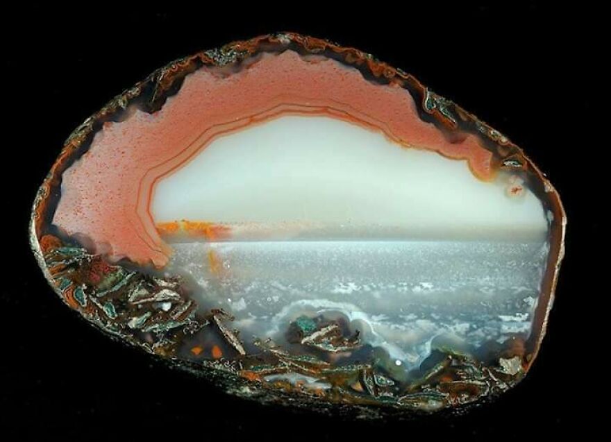 Cross-section of a rock resembling a scenic ocean view, showcasing accidental art in nature.