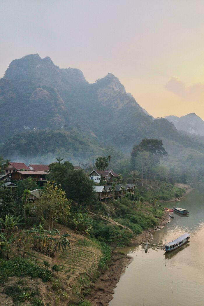 Village beside a river in a mountainous landscape, showcasing incredible world photos.