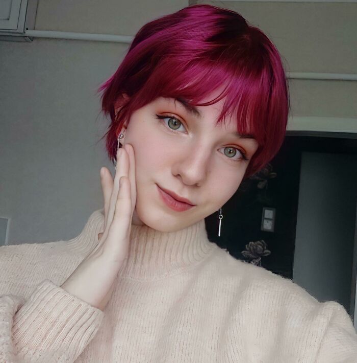 Person with vibrant magenta hair and a light sweater, illustrating changing hair color style.