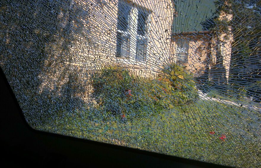 Shattered glass window creating an accidental art effect with a view of a house and garden.