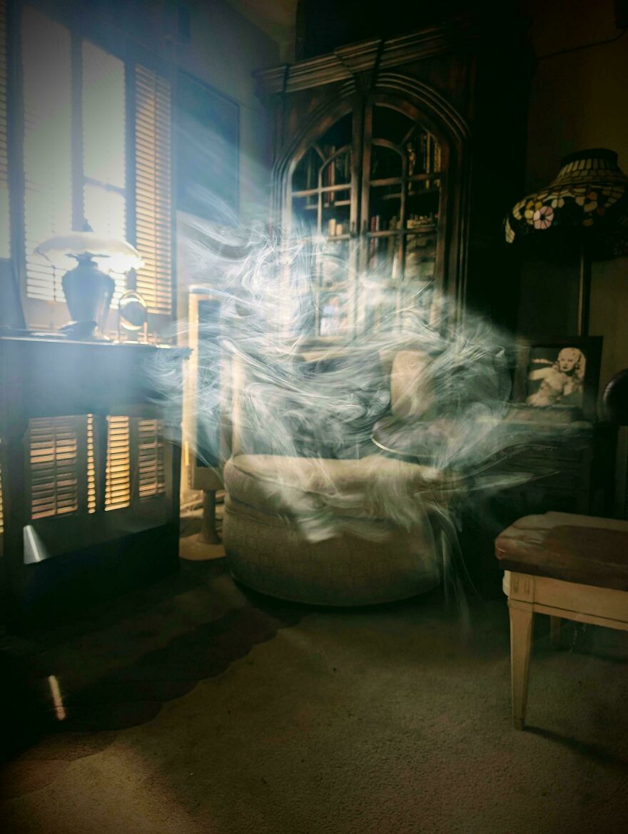 Sunlight and smoky patterns create accidental art in a cozy room setting, with a chair and bookshelf in the background.