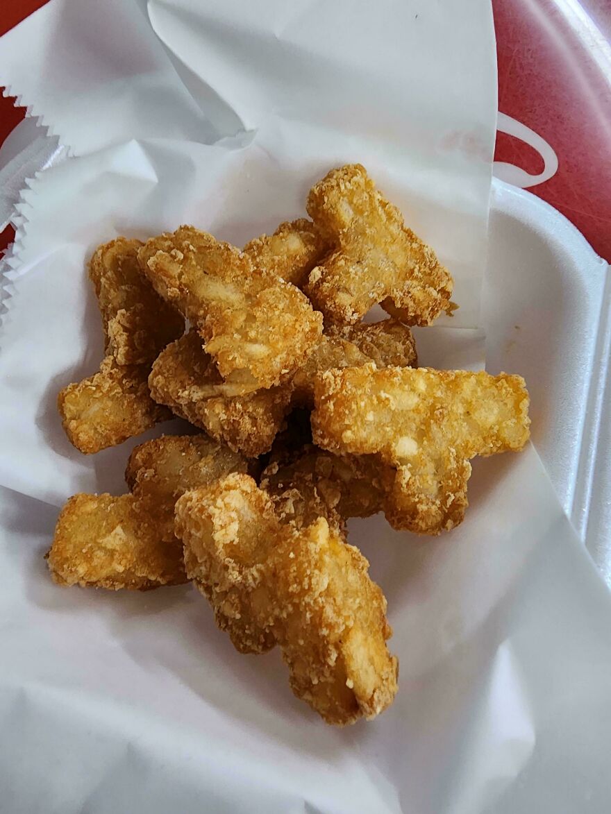 Golden brown fries that look like chicken nuggets on white paper.