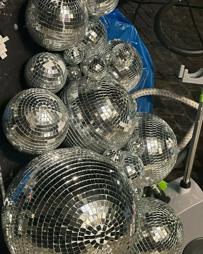 Disco balls stacked on a New York City curb, reflecting light and colors. Perfect for 'stooping' treasure hunters.