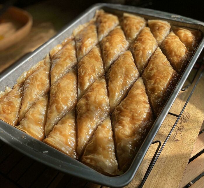 Baklava in a tray, beautifully arranged and glazed, showcasing elevated baking skills.