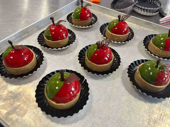 Culinary concoctions: mini apple tarts with glossy red and green coatings on a baking tray.