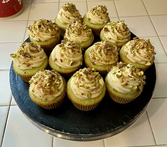 Cupcakes with pistachio topping on a black platter, showcasing creative culinary concoctions.