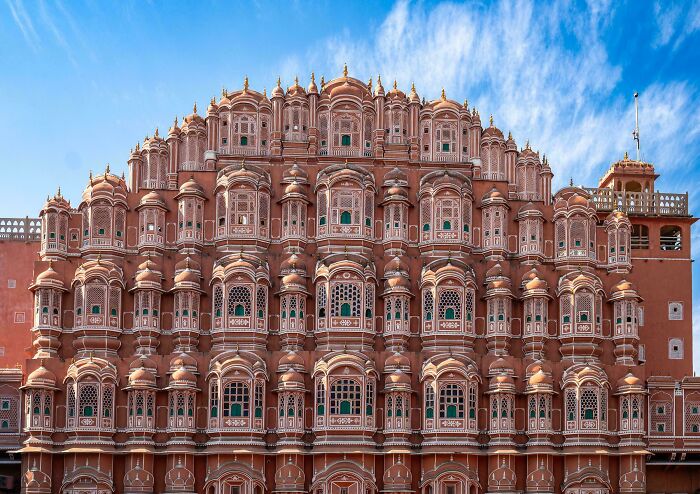 Intricately designed historic building showcasing impressive architectural feats under a bright blue sky with wispy clouds.