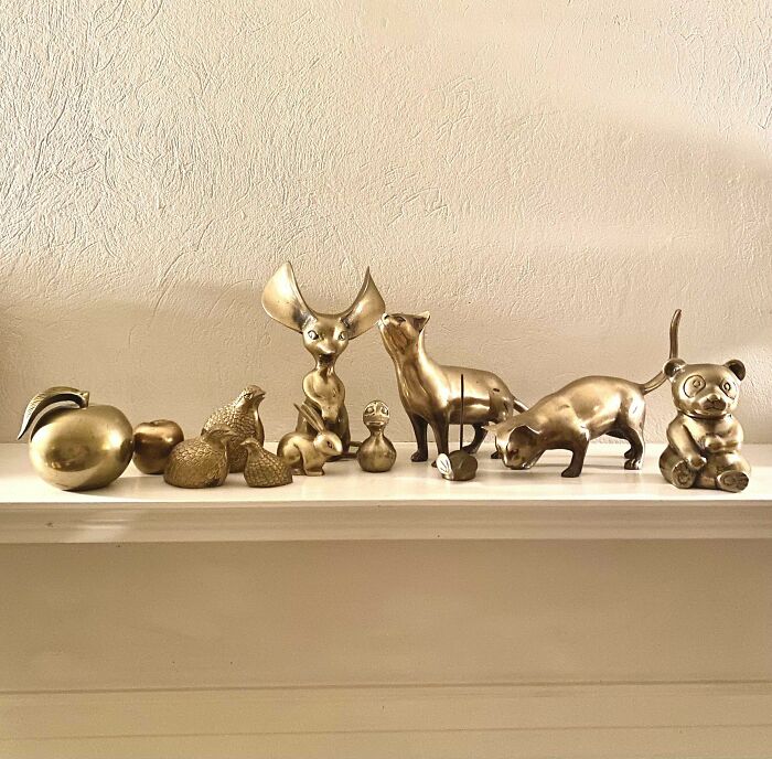 Gold animal figurines found while thrifting, including a dog, cat, and rabbit, displayed on a white shelf.