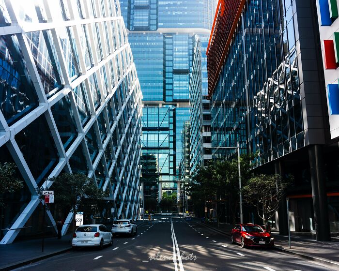 City street in Australia with modern skyscrapers and parked cars, showcasing urban architecture.