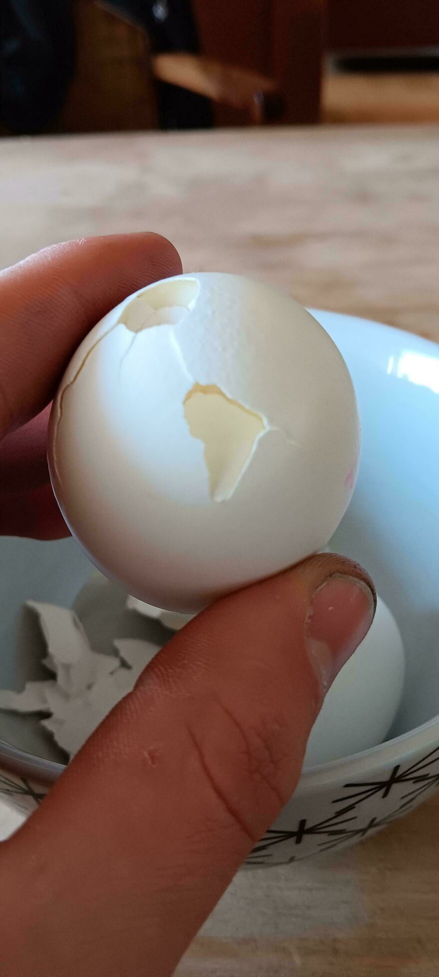 C*****d egg shell resembling continents, held over a bowl.