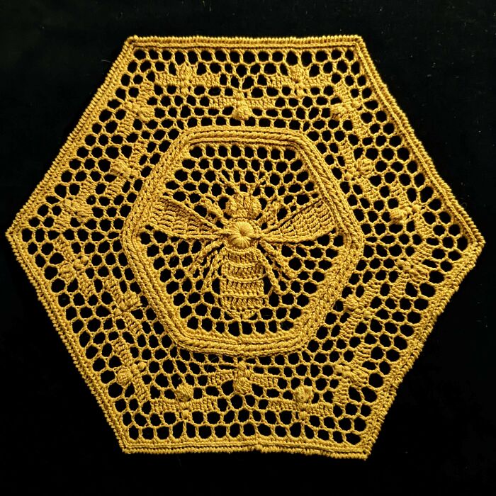 Hexagonal crochet featuring a detailed bee pattern on black background.
