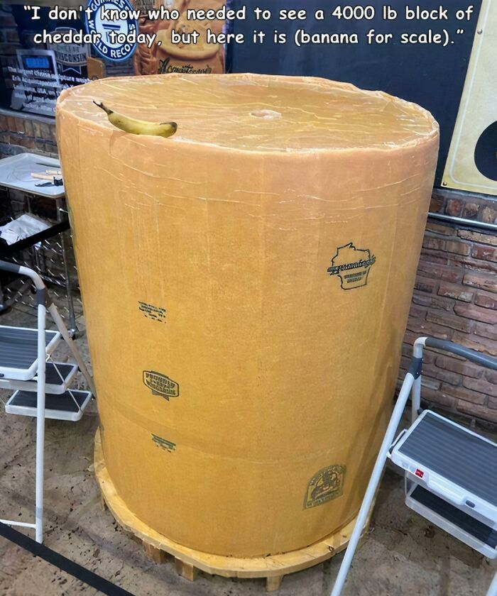A massive block of cheddar cheese with a banana for scale, showcasing an absolute-unit-sized object.