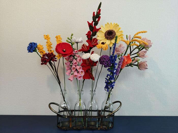 Crocheted flowers in glass vases, showcasing incredible crochet artistry and vibrant colors against a neutral background.