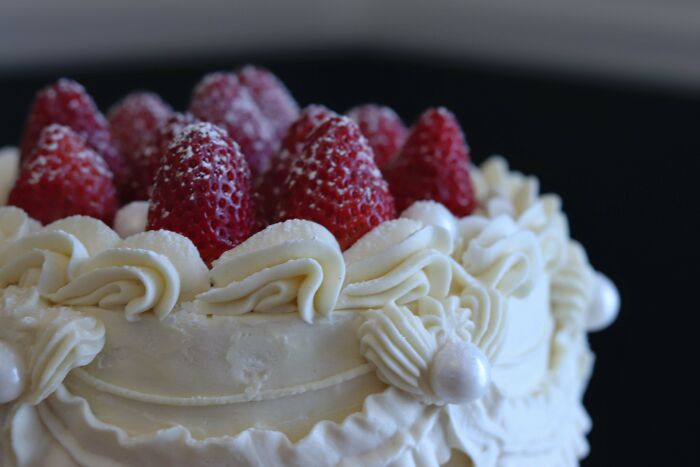 Elegantly decorated cake with frosting and fresh strawberries, showcasing exceptional bakers' culinary creativity.
