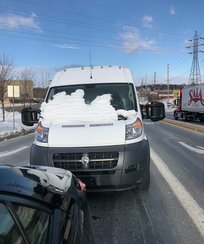 Van with snow-covered windshield blocking driver's view on the road, illustrating risky driving behavior.