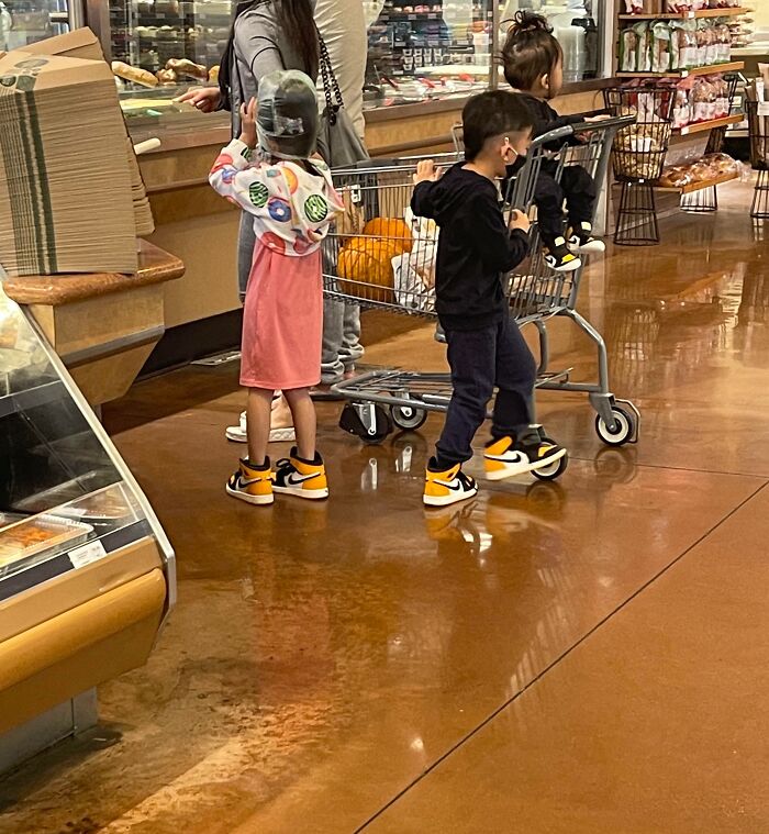 Children in a grocery store, one child wearing a plastic dome on their head, demonstrating ignorant-parents behavior.