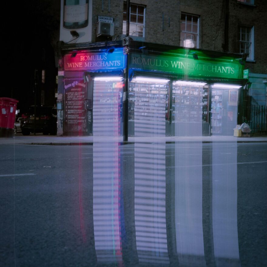 Colorful lights create an accidental art effect on a shop facade at night.