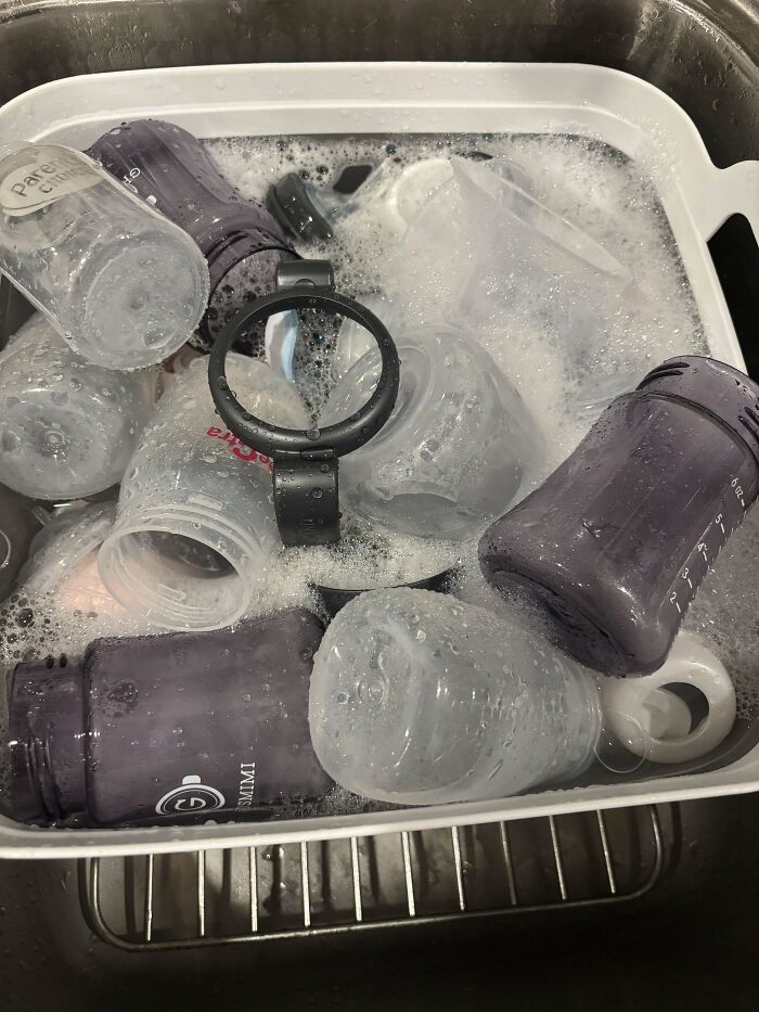 Clean baby bottles soaking in a tub, showcasing the rewarding duties of being a dad.