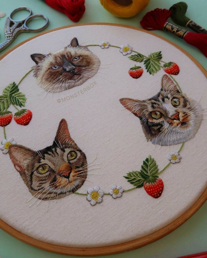Embroidery designs featuring realistic cat faces with strawberries and flowers in a circular pattern on fabric.