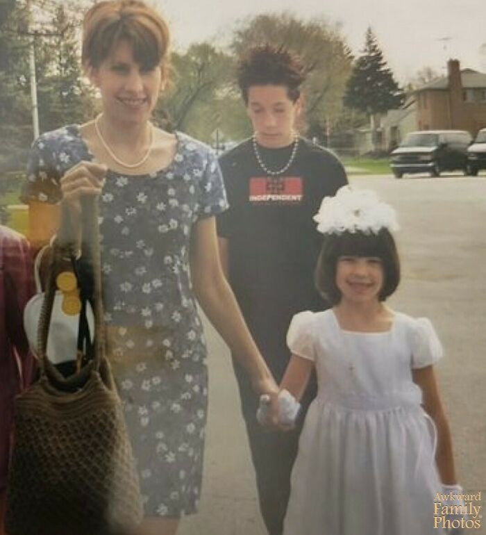 A family walking outside with a mother in a floral dress and a smiling child in a white dress, capturing awkward family photos.