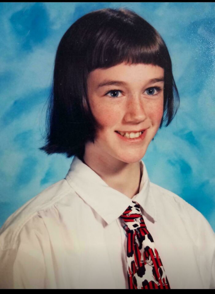 Young person's school photo with retro haircut, wearing a white shirt and patterned tie, showcasing a "blunder years" style.