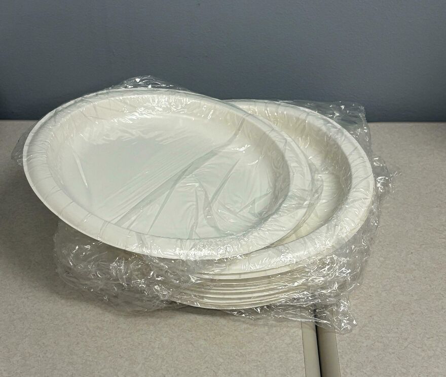 Stack of paper plates wrapped in excessive plastic, highlighting wasteful unnecessary packaging.