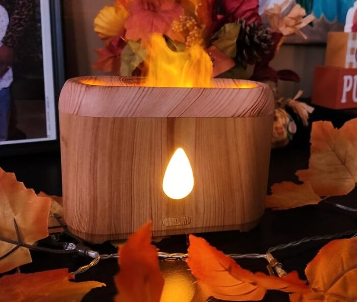 Wooden aroma diffuser surrounded by autumn leaves, ideal cozy product for relaxing indoors.