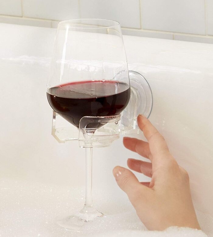 A glass of wine in a bath cup holder, ideal for cozy relaxation indoors.