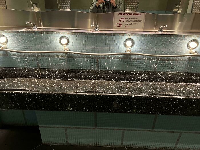 Unfortunate public interior design with a sink causing water to splash onto the floor due to poor faucet placement.