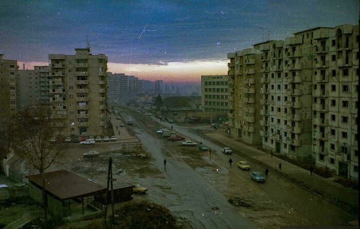 Urban hell scene with decaying high-rise buildings and a desolate street at sunset.