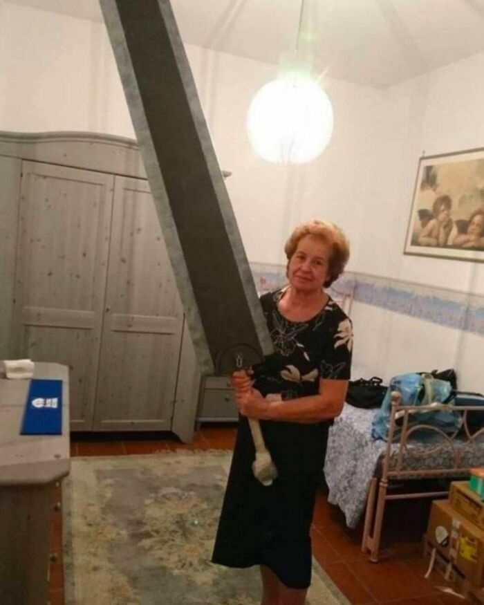 Older woman holding an oversized sword indoors, a weird side of the internet photo showing unusual objects and scenes.