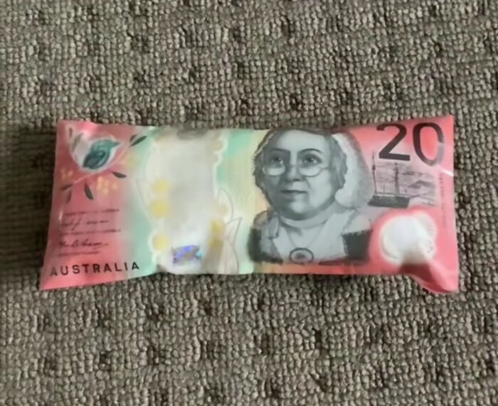Australian $20 note encased in ice on a textured surface, part of a surprising community post.
