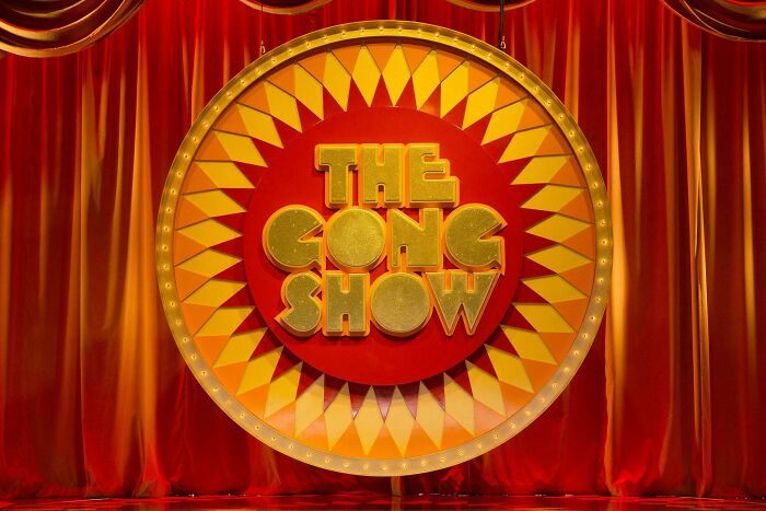 Vintage game show set with a bright circular sign reading The Gong Show, evoking nostalgic photos and memories.