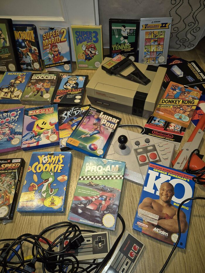 Vintage Nintendo games and consoles found while thrifting, including Super Mario and Pac-Man, displayed on a wooden floor.