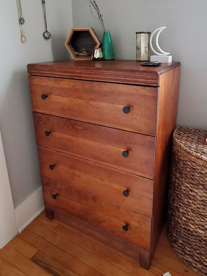 Wooden dresser with simple decor, ironic statement on consumerism choices.