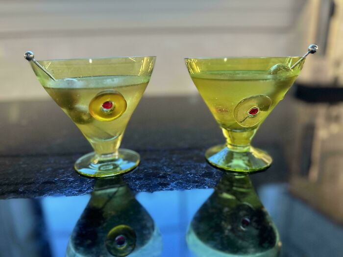 Two martini glasses with olives on a reflective surface, representing funny wholesome anniversary surprises.