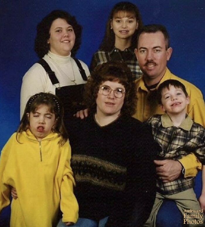 Family portrait with awkward expressions and mismatched outfits capturing a sweet and memorable family moment.