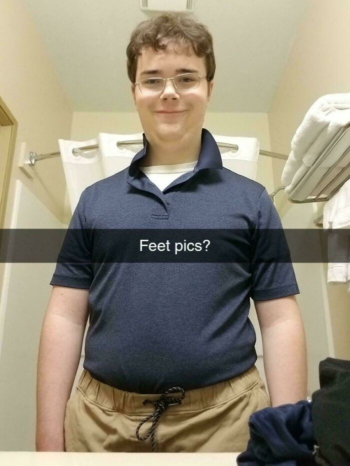 Young person in a bathroom wearing glasses and a blue shirt, with text overlay: "Feet pics?". Blunder years photo.