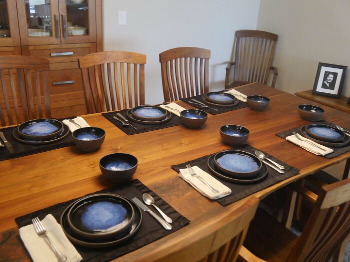 Elegant wooden dining table set with blue DIY dishware and neatly arranged silverware.