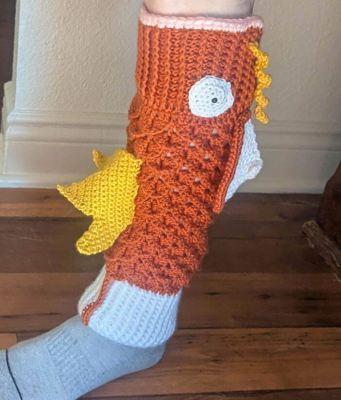 Crochet enthusiast proudly wearing a colorful handmade bird-themed crochet leg warmer with detailed stitching.
