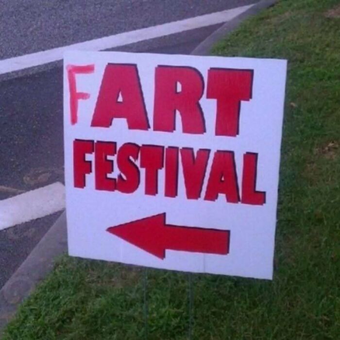 Sign on grass with red letters partially spelling art festival and arrow, a random photo for processing ideas.