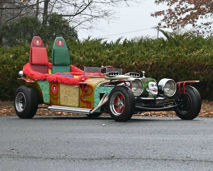 Custom vintage hot rod car with colorful seats and Joker-themed decoration, a nostalgic photo from classic car culture.
