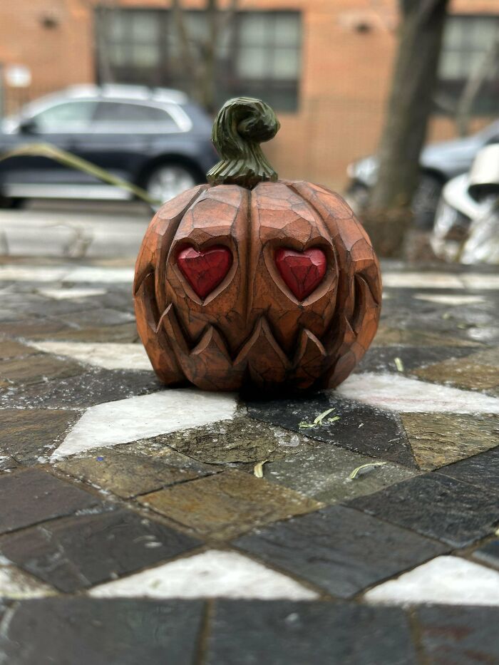 Carved pumpkin with heart-shaped eyes, featured in amazing DIY projects, on a mosaic pavement background.