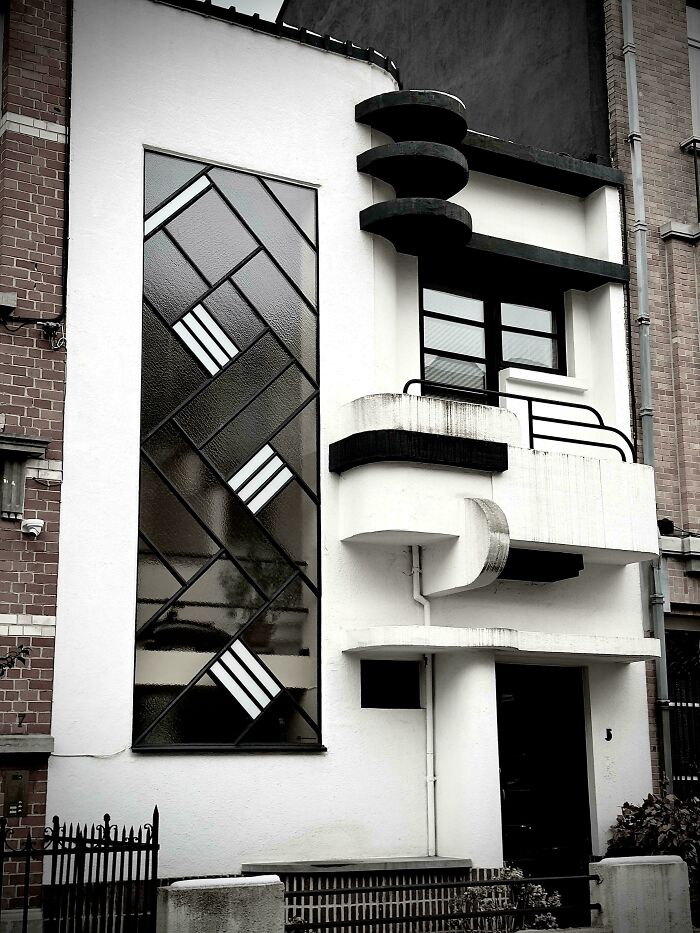 Modern architectural feat on a white building featuring geometric black window panels and curved balcony design.