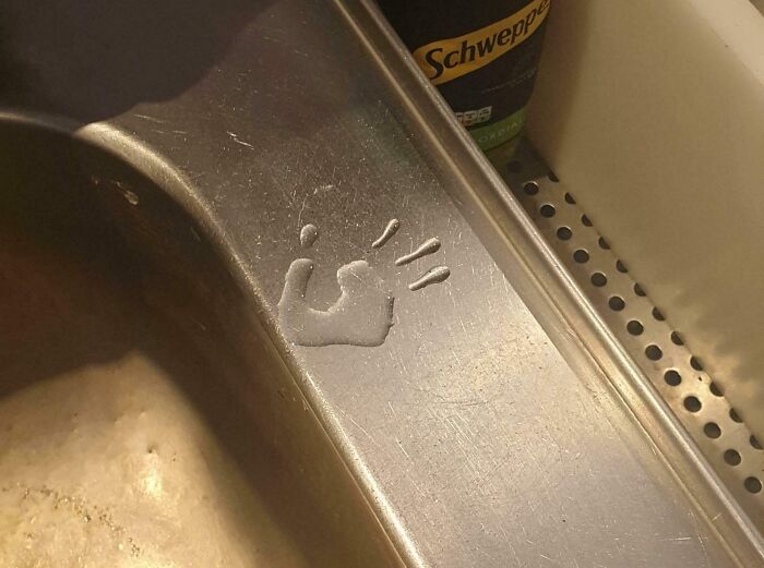 Water stain resembling a smiley face on a kitchen sink, showcasing pareidolia.