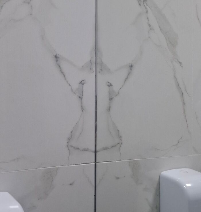 Marble wall tiles resembling a human figure, demonstrating pareidolia effects.